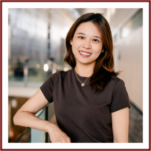 Headshot of Asian woman with medium length red-brown hair, wearing a dark brown t-shirt and a gold necklace