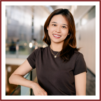 Headshot of Asian woman with medium length red-brown hair, wearing a dark brown t-shirt and a gold necklace