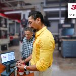 two men stand and talk in a lab with scientific equipment.