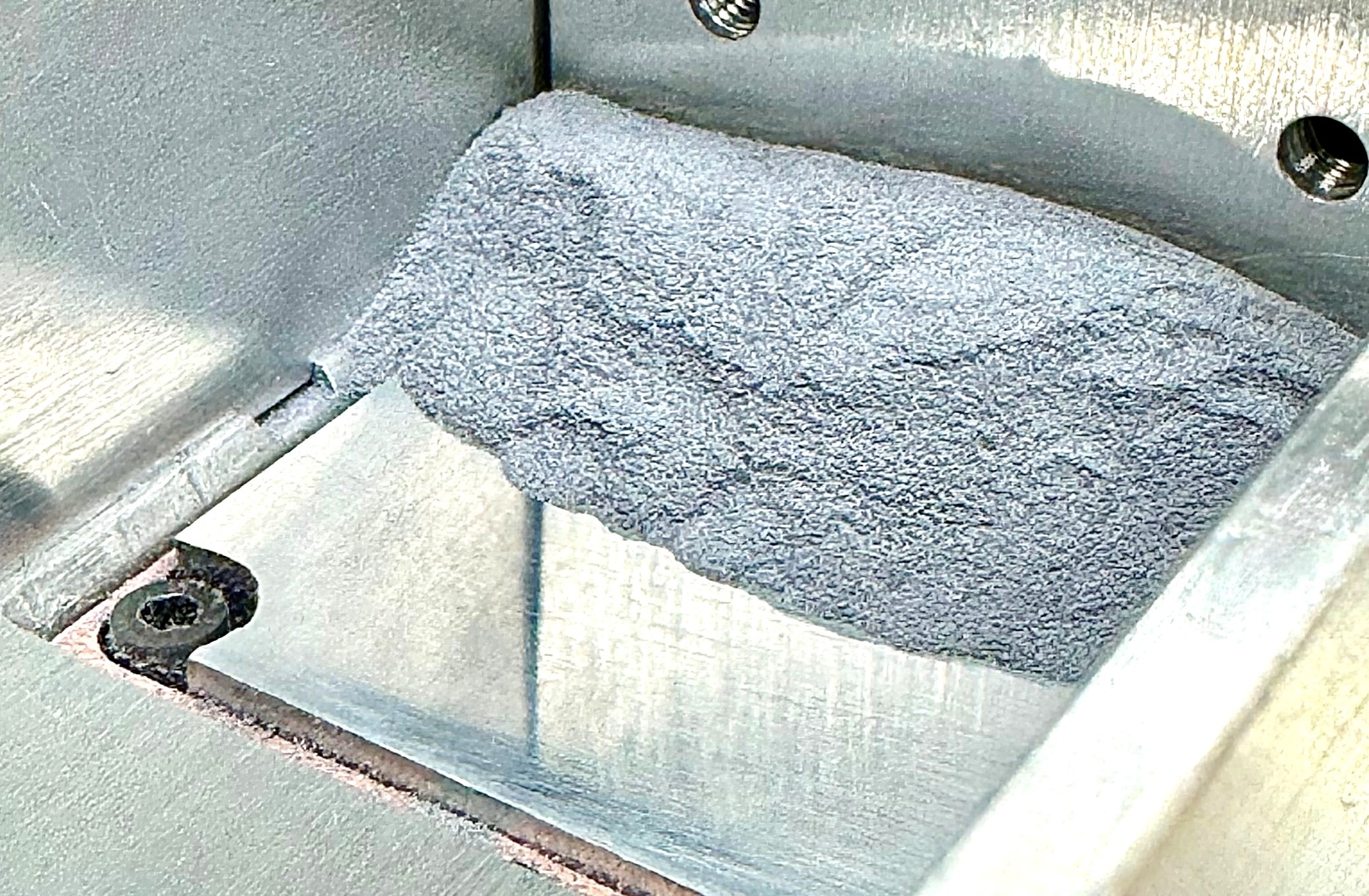 a metal bin with silver-gray powder piled on one side