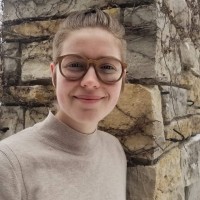 headshot of a white person with blond hair and glasses