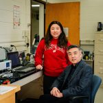 Asian woman with long brown hair standing next to an Asian man with short black hair.