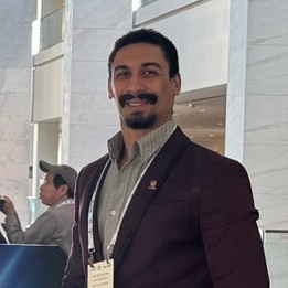 headshot of a man with brown skin, short black hair, and a goatee