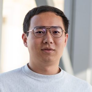 headshot of an asian man with short black hair and glasses