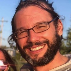 headshot of a white man with brown hair, a beard, and glasses