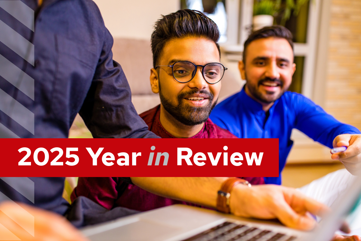 Young middle eastern man wearing glasses and smiling while looking at a computer someone is holding