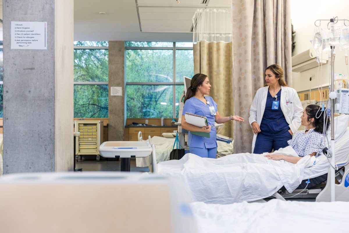 nurse, doctor, and patient in conversation around bedside